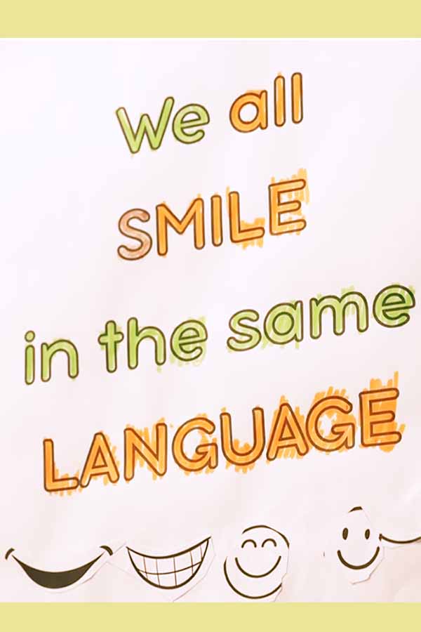 A hand-drawn poster that says We all smile in the same language