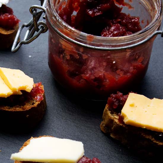 A half empty pot of Beetroot Relish with some bread and cheese with the relish
