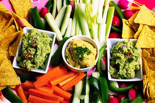 Veg sticks, tortilla chips with guacamole and yellow-pepper hummus